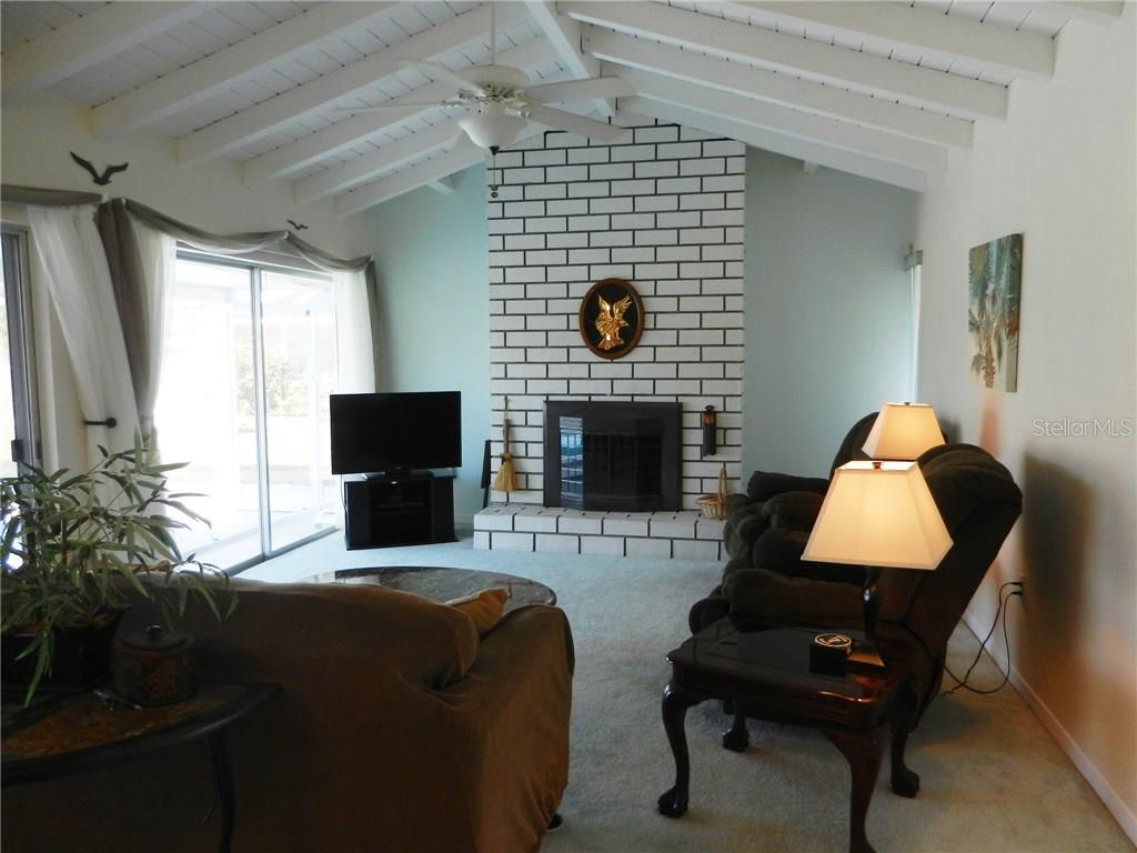 A living room features a white brick fireplace, vaulted ceiling, and light blue walls — 98 CADDY ROAD, ROTONDA WEST, FL