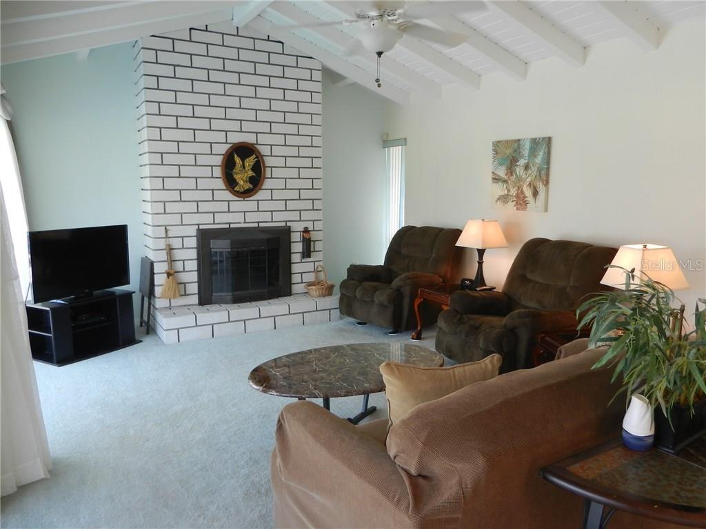 A living room features a white brick fireplace, light blue walls, and a sliding glass door — 98 CADDY ROAD, ROTONDA WEST, FL