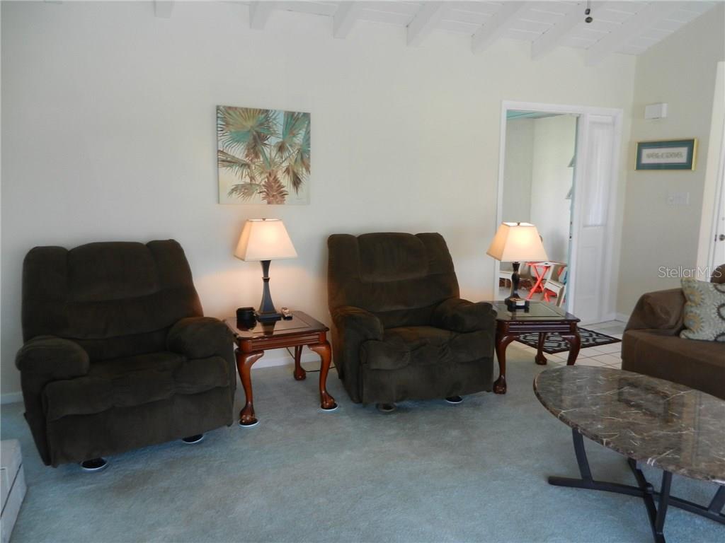 A living room with a light blue sofa and recliner leads to a dining area — 98 CADDY ROAD, ROTONDA WEST, FL
