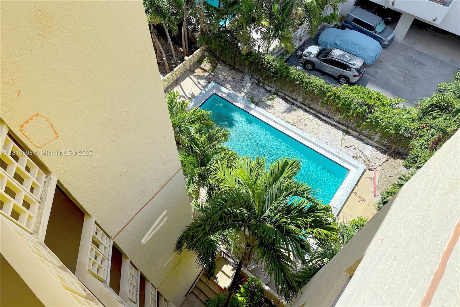An aerial view shows a rectangular swimming pool surrounded by palm trees and a parking area — 600 NE 25th St, Miami FL 33137, MIAMI, FL