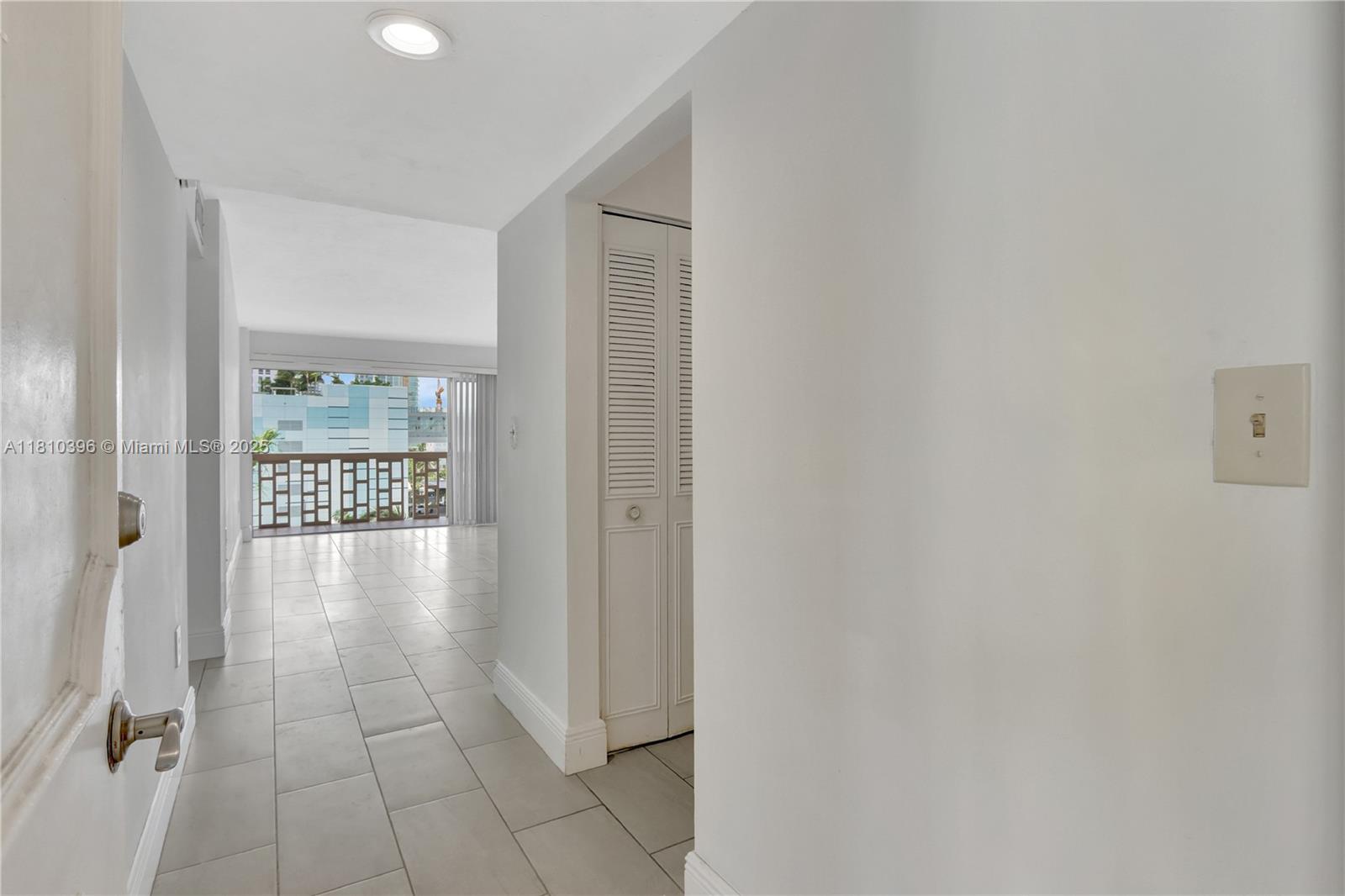 A hallway with light tile flooring leads to a living area with a balcony — 600 NE 25th St, Miami FL 33137, MIAMI, FL