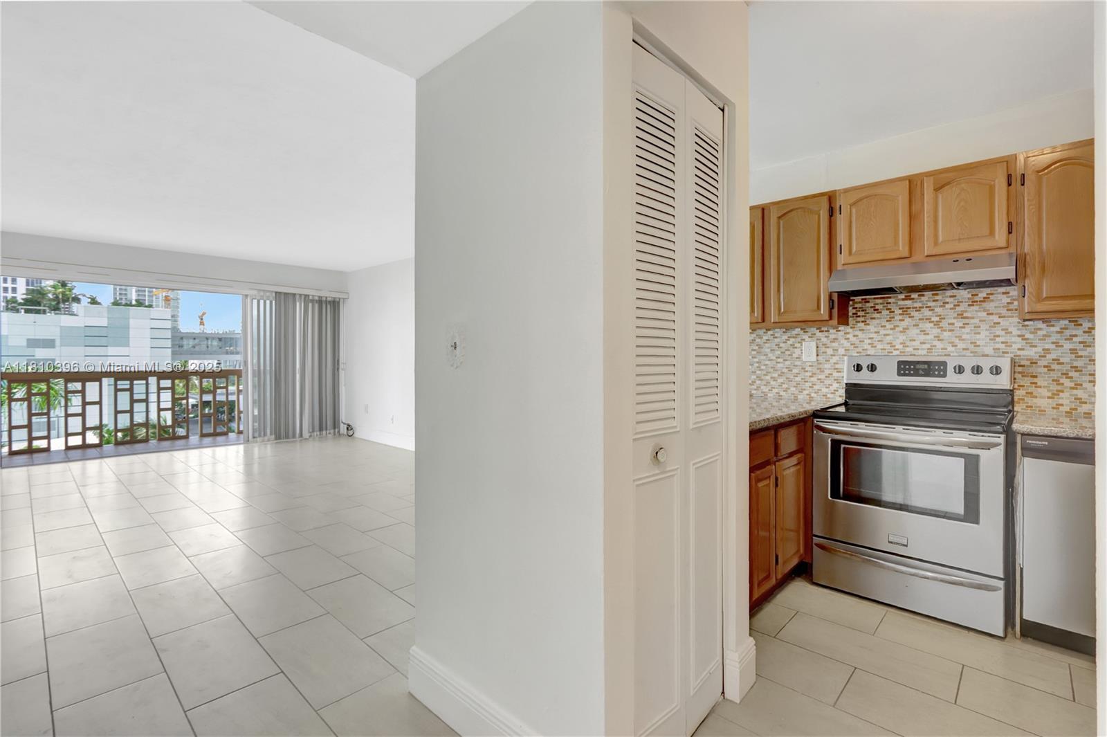 A kitchen with wood cabinets and stainless steel appliances opens to a tiled living area — 600 NE 25th St, Miami FL 33137, MIAMI, FL
