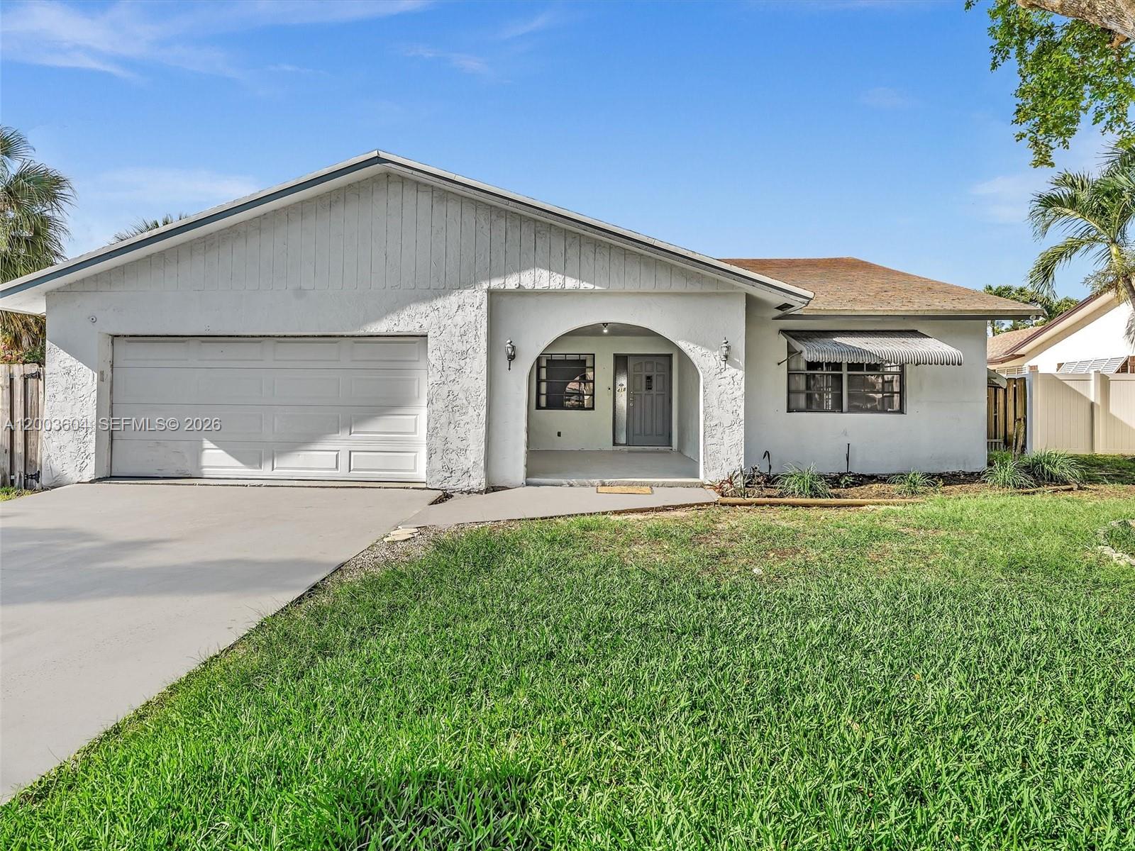 A single-story house with a white stucco facade, a garage, and an arched entryway — DANIA BEACH, FL