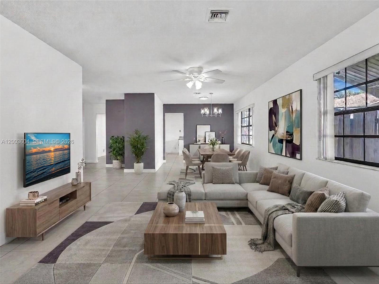 A modern living room features a sectional sofa, a wooden coffee table, and tile flooring — DANIA BEACH, FL