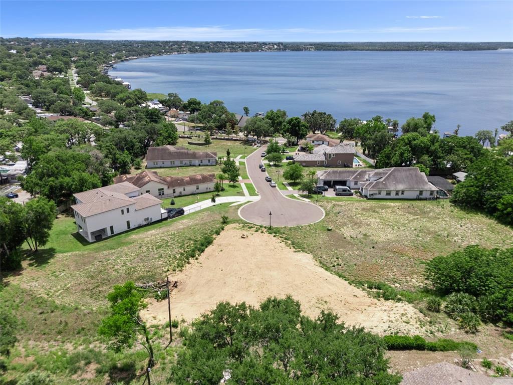 An aerial view shows a vacant residential lot situated near a large lake and houses — 1849 MOORINGS COURT, CLERMONT, FL
