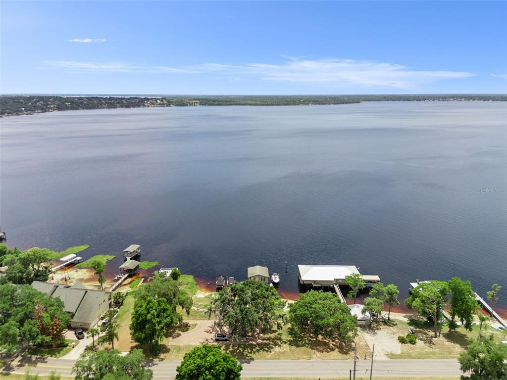 An aerial view shows a lakefront property with several boat docks and a house — 1849 MOORINGS COURT, CLERMONT, FL