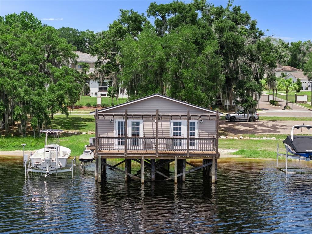 A stilted boathouse with a wooden deck sits on the edge of a lake — 1849 MOORINGS COURT, CLERMONT, FL