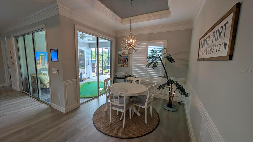 A kitchen island with a double sink overlooks a living room with a wall-mounted television — 3369 BILLBERRY STREET, NORTH PORT, FL