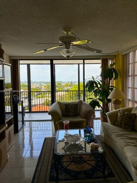 A living room features a ceiling fan, tiled floors, and a balcony with water views — 2500 NE 135th St # C611, North Miami FL 33181, NORTH MIAMI, FL