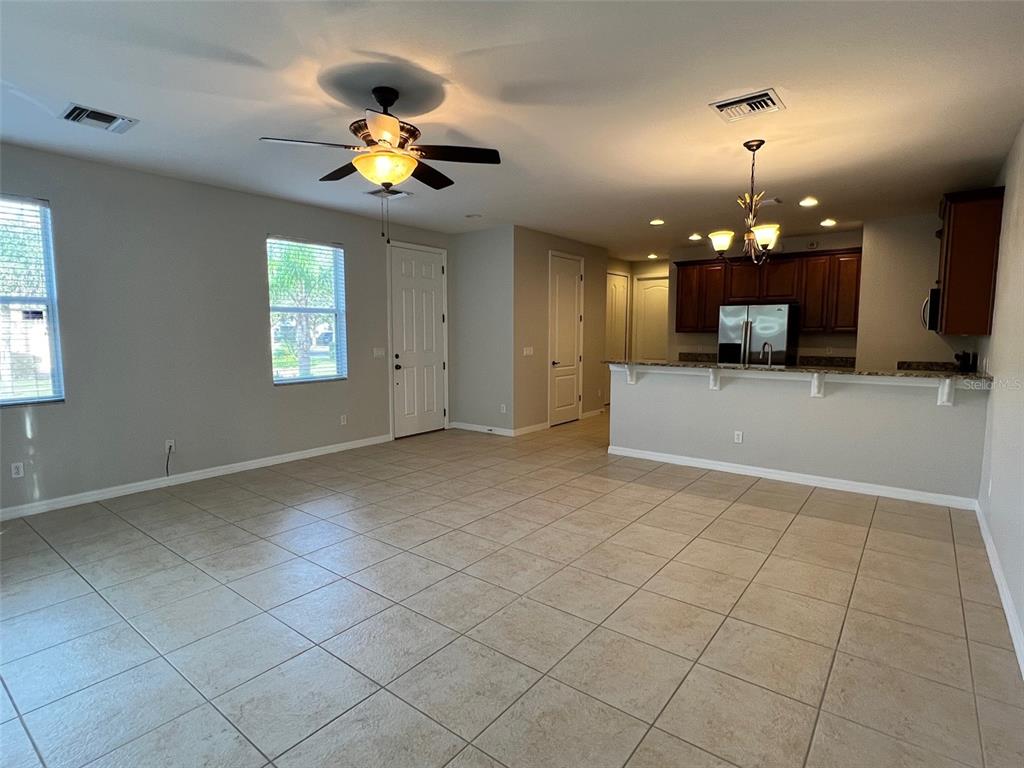 An open-concept living room features tile flooring, a ceiling fan, and an adjacent kitchen — 1853 GARDEN SAGE DRIVE, OVIEDO, FL