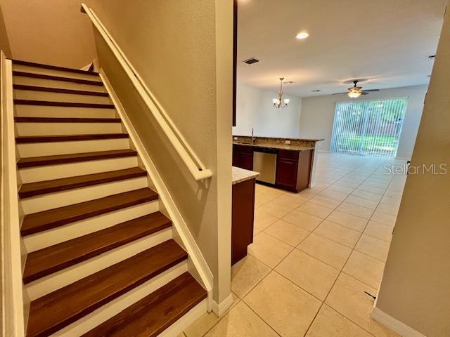 A staircase with wood treads leads to an open-concept kitchen and living area with tile — 1853 GARDEN SAGE DRIVE, OVIEDO, FL