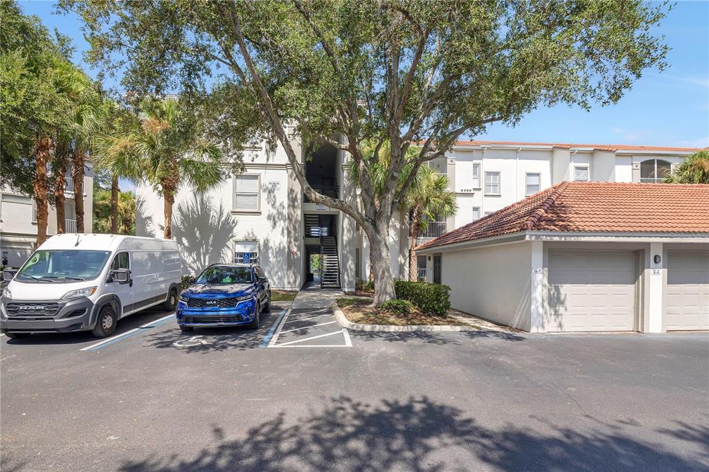 A multi-story apartment building exterior features a parking lot, a white van, and garages — 2615 MAITLAND CROSSING WAY UNIT 104, ORLANDO, FL