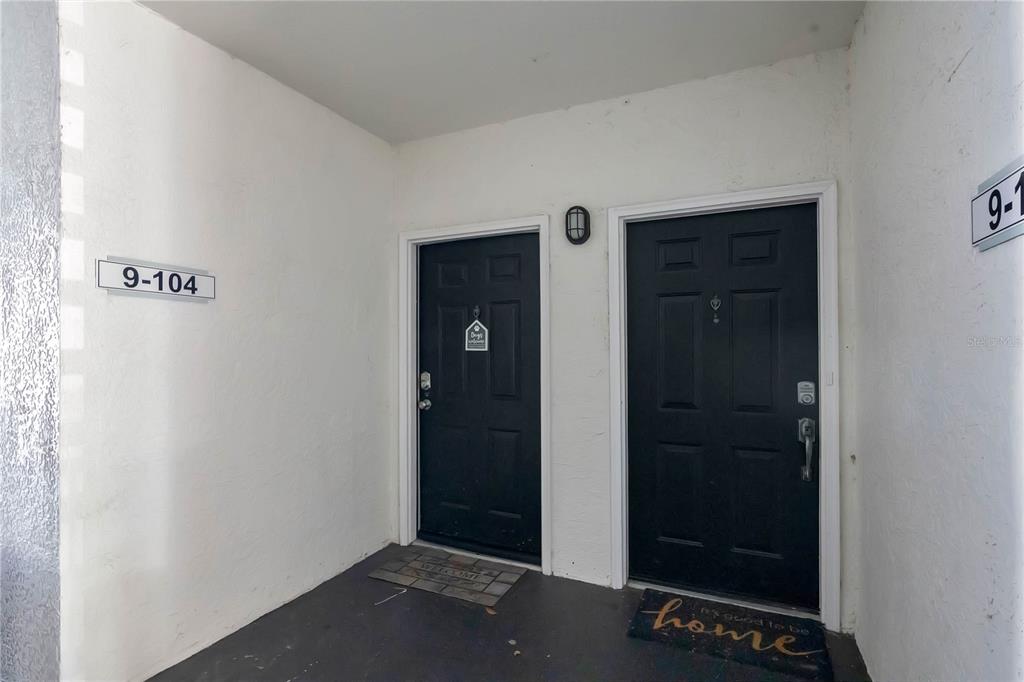 Two black front doors are situated side-by-side on a covered concrete porch — 2615 MAITLAND CROSSING WAY UNIT 104, ORLANDO, FL
