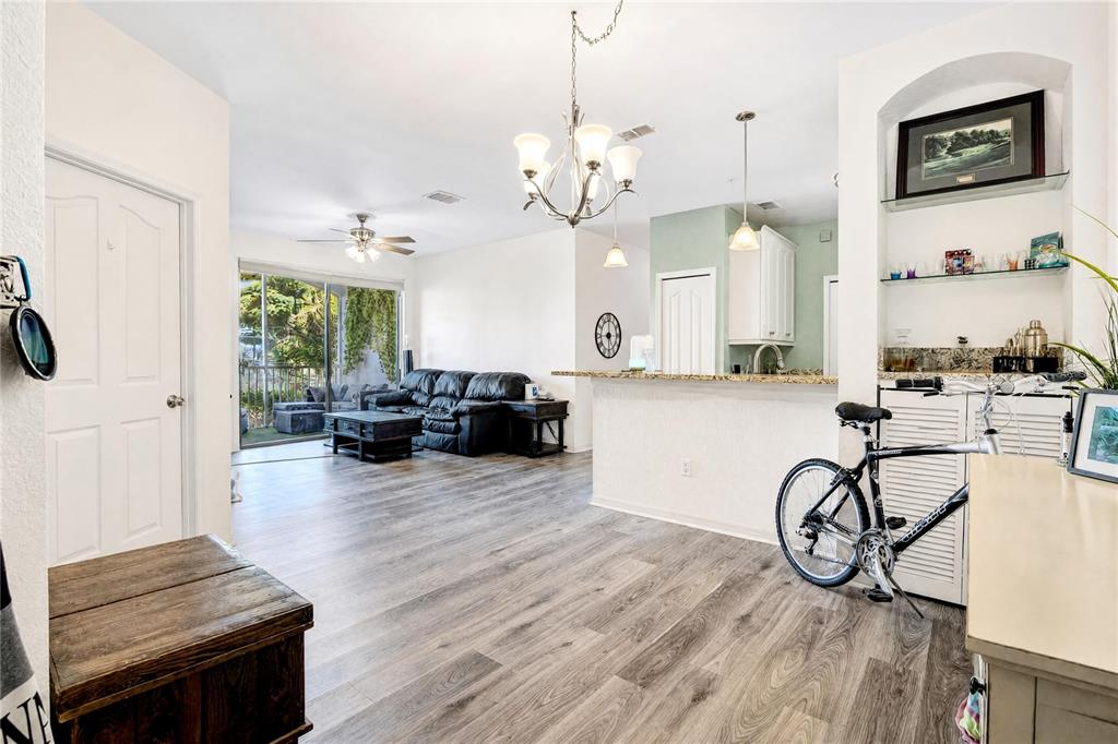 An open-concept living area features wood-look flooring, a kitchen island, and a black bicycle — 2615 MAITLAND CROSSING WAY UNIT 104, ORLANDO, FL