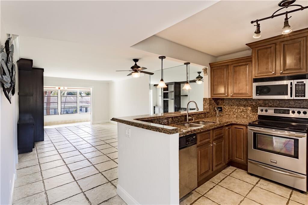 A kitchen with granite countertops and stainless steel appliances overlooks an open-concept living area — 2800 Fiore Way # 2060, Delray Beach FL 33445, DELRAY BEACH, FL