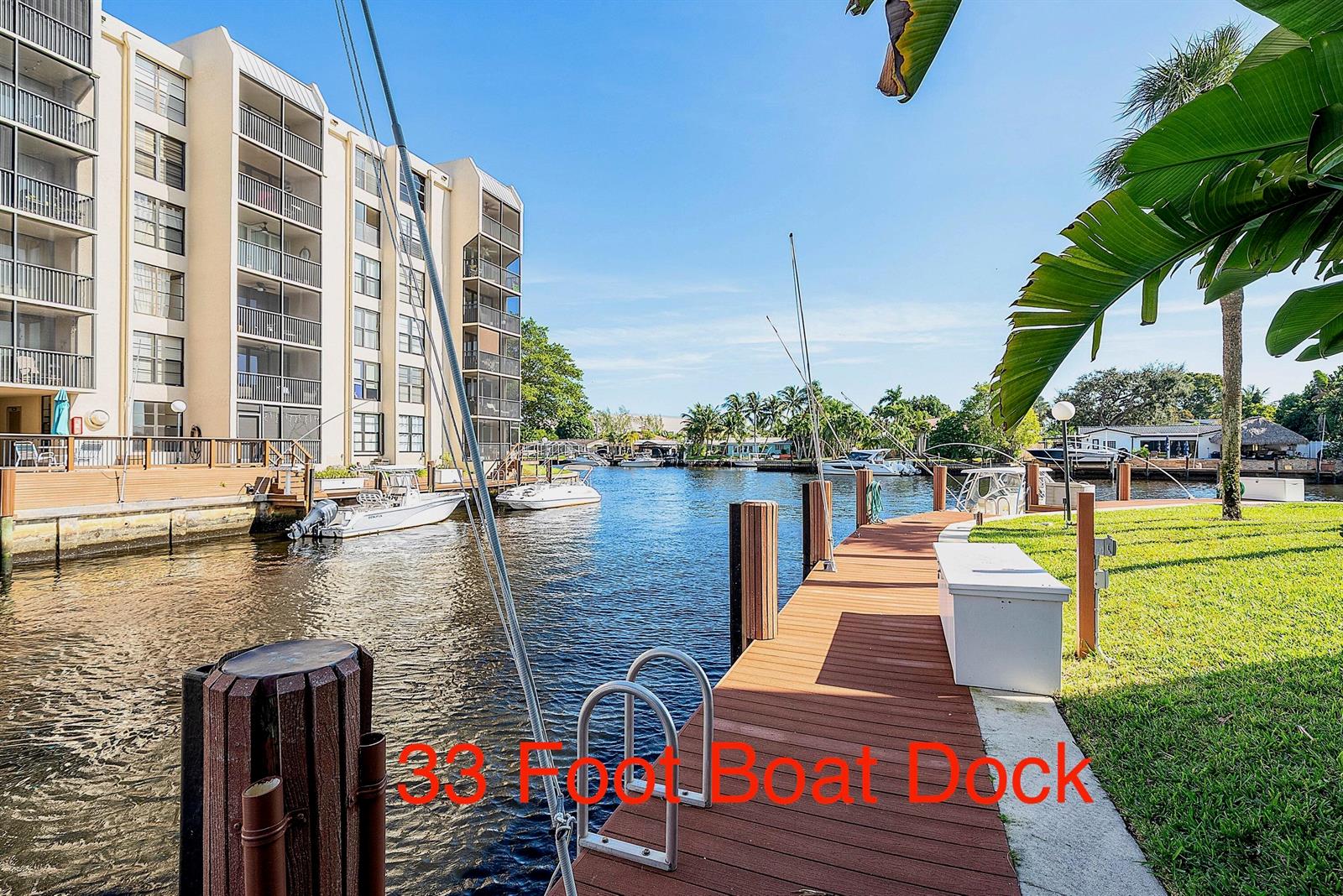 A wooden boat dock extends along a canal next to a multi-story apartment building — 18 Royal Palm Way Way # 109, Boca Raton FL 33432, BOCA RATON, FL
