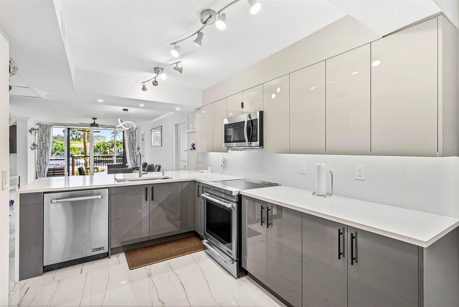 A modern kitchen features gray lower cabinets, glossy beige upper cabinets, and white quartz countertops — 18 Royal Palm Way Way # 109, Boca Raton FL 33432, BOCA RATON, FL