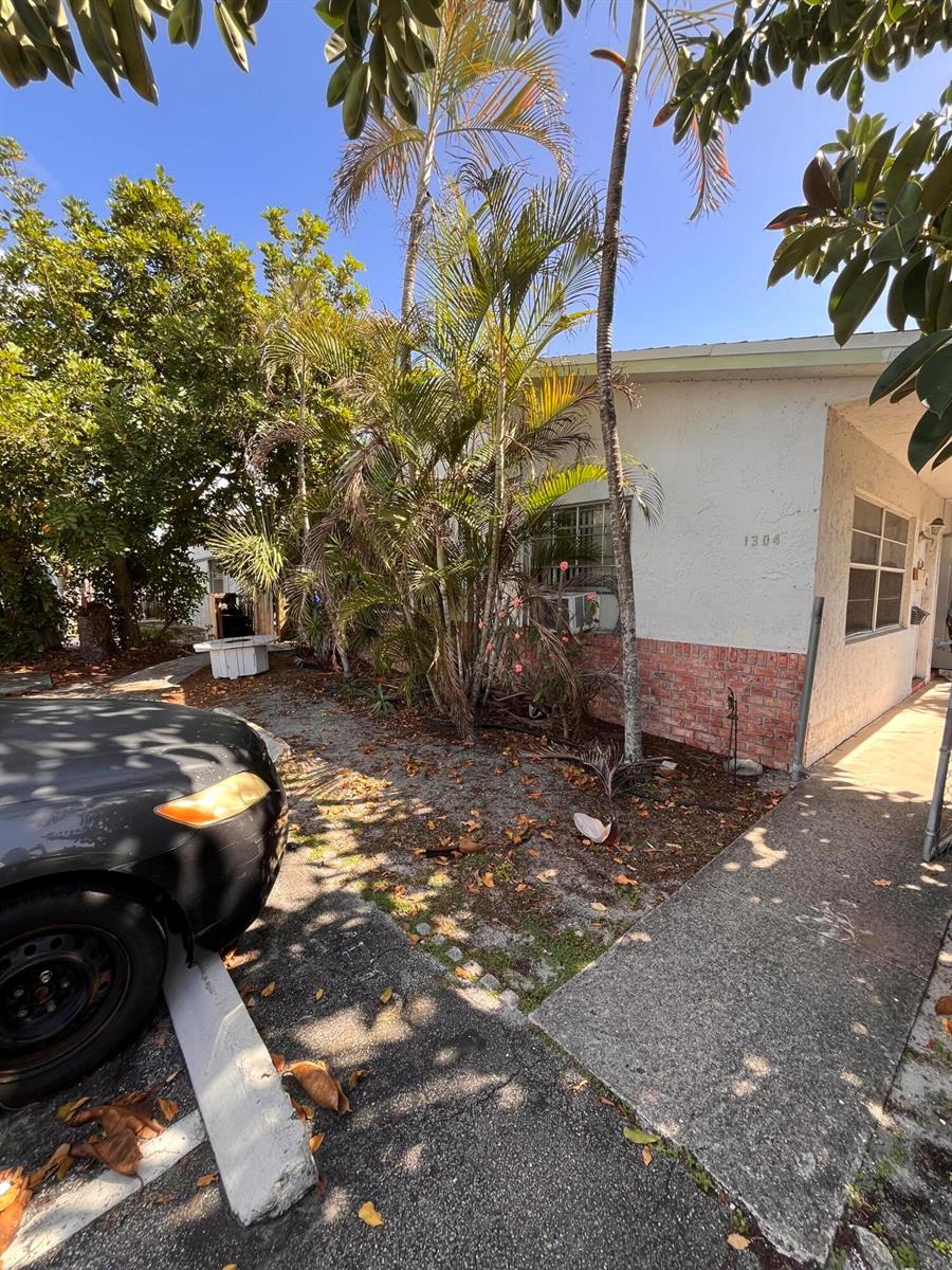 A view of a building exterior with a brick base, palm trees, and a car — 1304 NE 4th Street, Pompano Beach FL 33060, POMPANO BEACH, FL