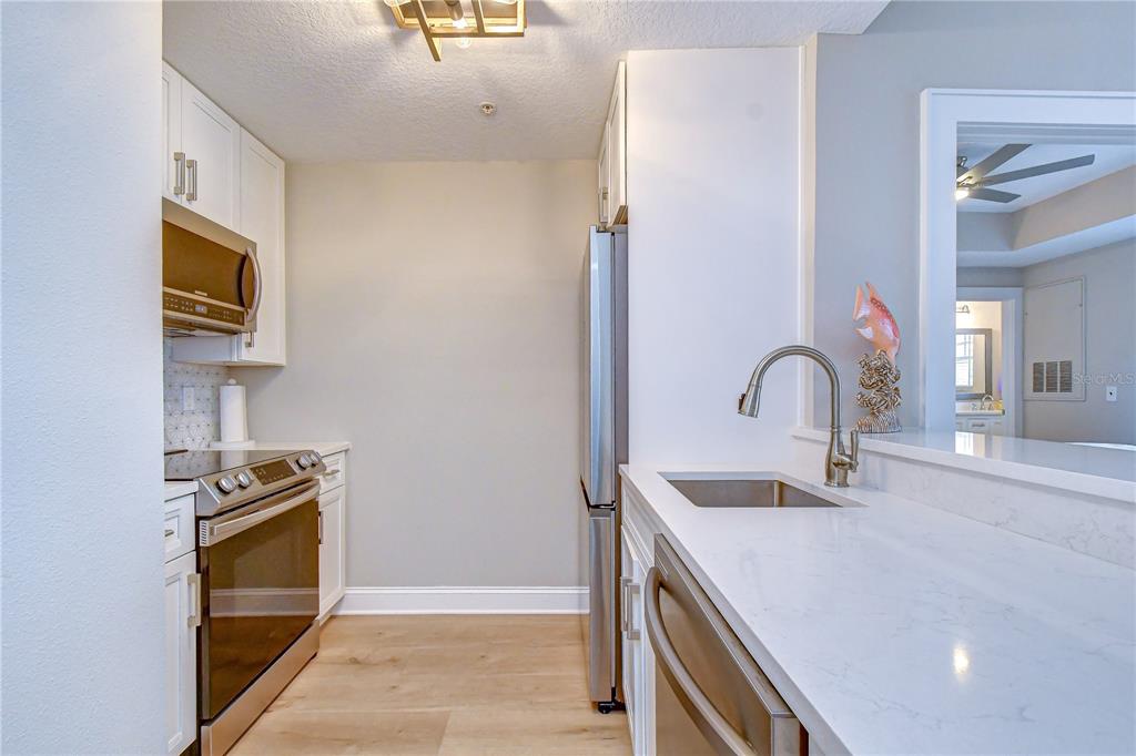 A kitchen features white cabinets, stainless steel appliances, and a white quartz countertop — 800 S DAKOTA AVENUE UNIT 121, TAMPA, FL