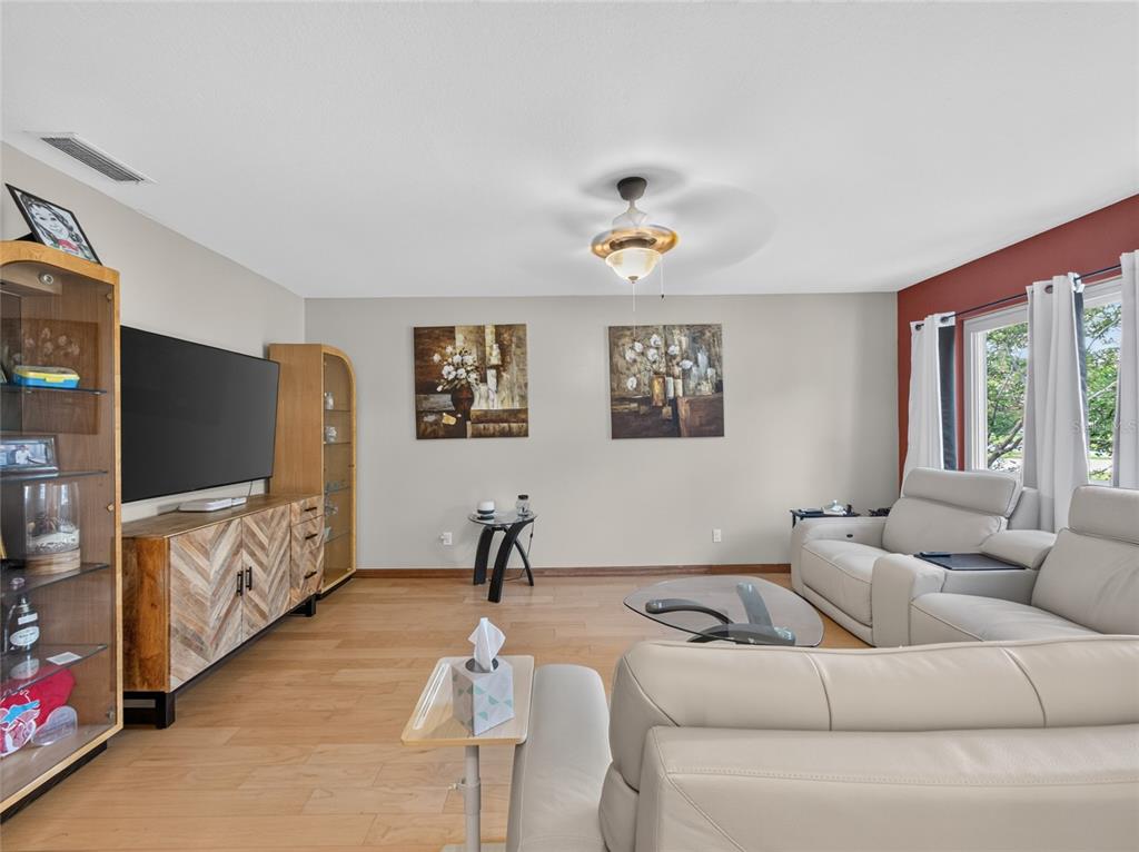 A living room features light wood flooring, a television console, and white leather sofas — 127 ROSE BRIAR DRIVE, LONGWOOD, FL