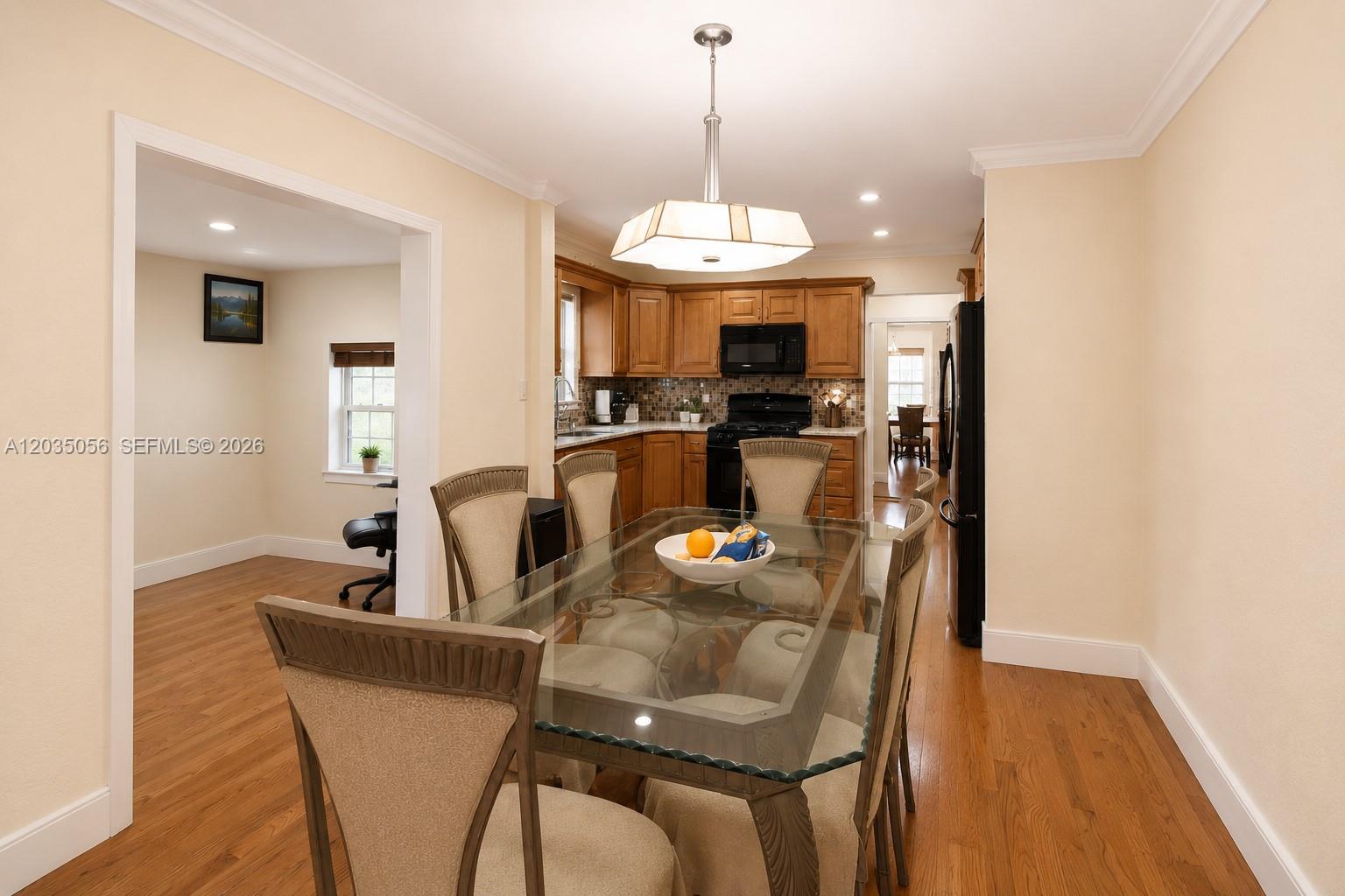 A dining area with a glass-topped table leads into a kitchen with wood cabinets — 316 S 24th Ave, Hollywood FL 33020, HOLLYWOOD, FL