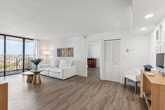 A bright living room features wood-look flooring, a white sofa, and a balcony with city views — AVENTURA, FL