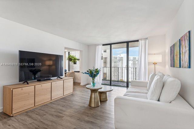 A living room features a wooden media console, a white sofa, and a balcony view — AVENTURA, FL