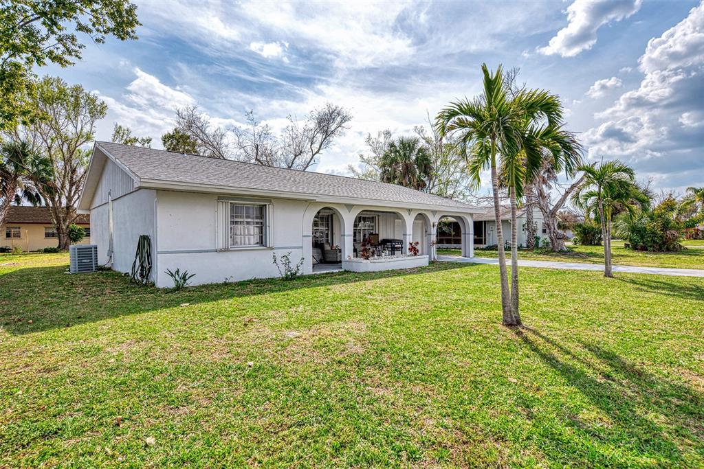 A single-story house with a covered front porch, palm trees, and a grassy lawn — 13479 NEWPORT AVENUE, PORT CHARLOTTE, FL