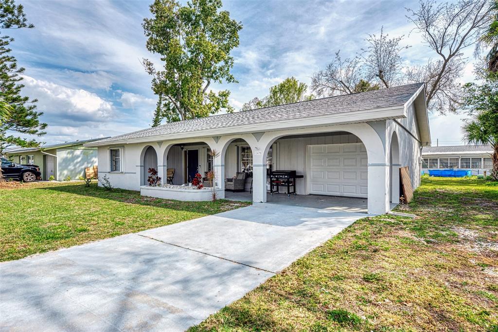 A single-story house with a white exterior, arched porch, and an attached garage — 13479 NEWPORT AVENUE, PORT CHARLOTTE, FL