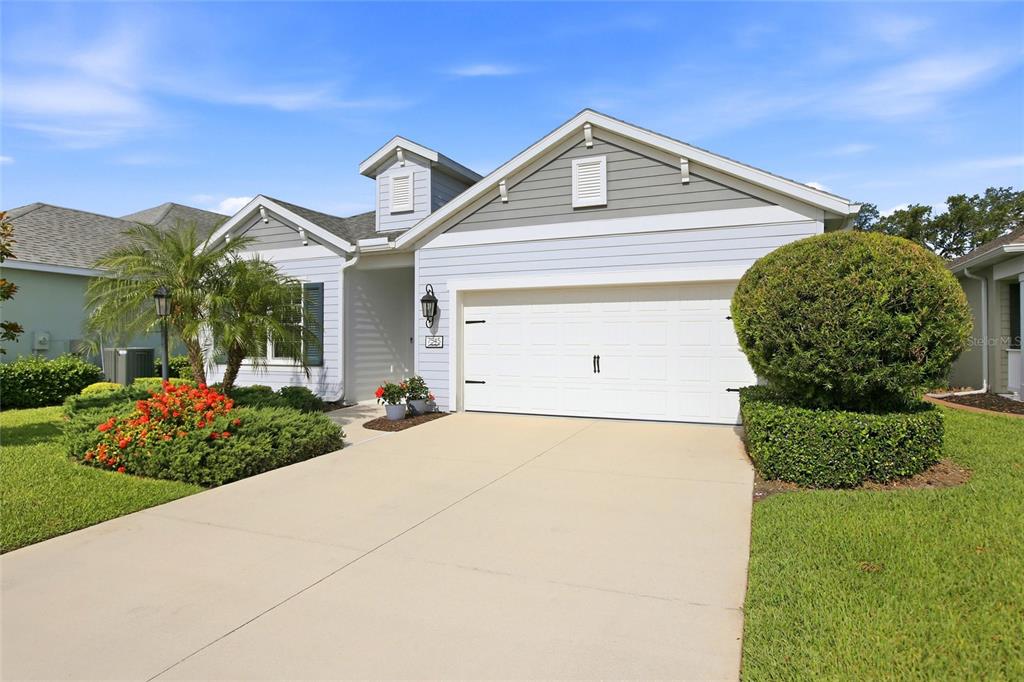 A light blue single-story house features a two-car garage, a driveway, and landscaped front yard — 7545 RIDGELAKE CIRCLE, BRADENTON, FL