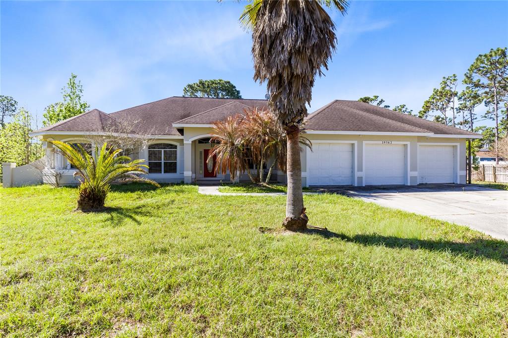 A single-story house with a three-car garage and palm trees in the front yard — 19562 MAJESTIC STREET, ORLANDO, FL