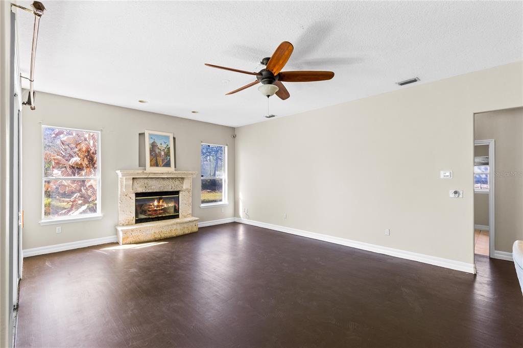 A living room with dark wood floors, a stone fireplace, and a ceiling fan — 19562 MAJESTIC STREET, ORLANDO, FL