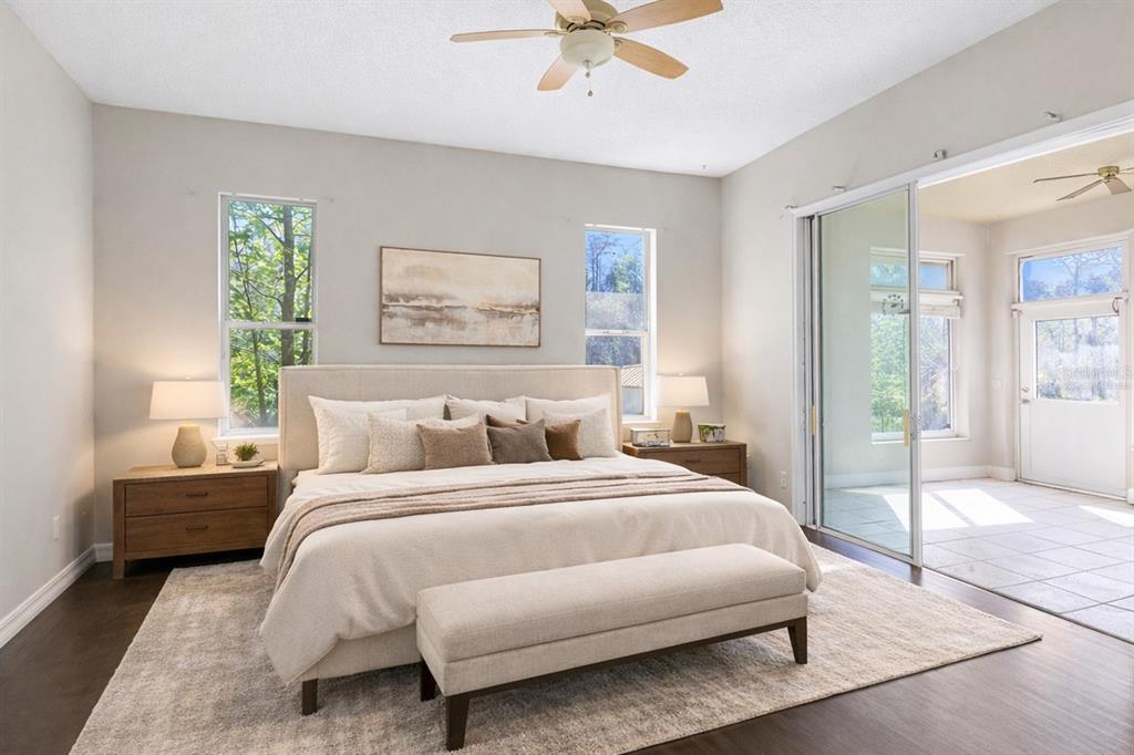 A bedroom features a king bed, two nightstands, a bench, and sliding doors to a patio — 19562 MAJESTIC STREET, ORLANDO, FL