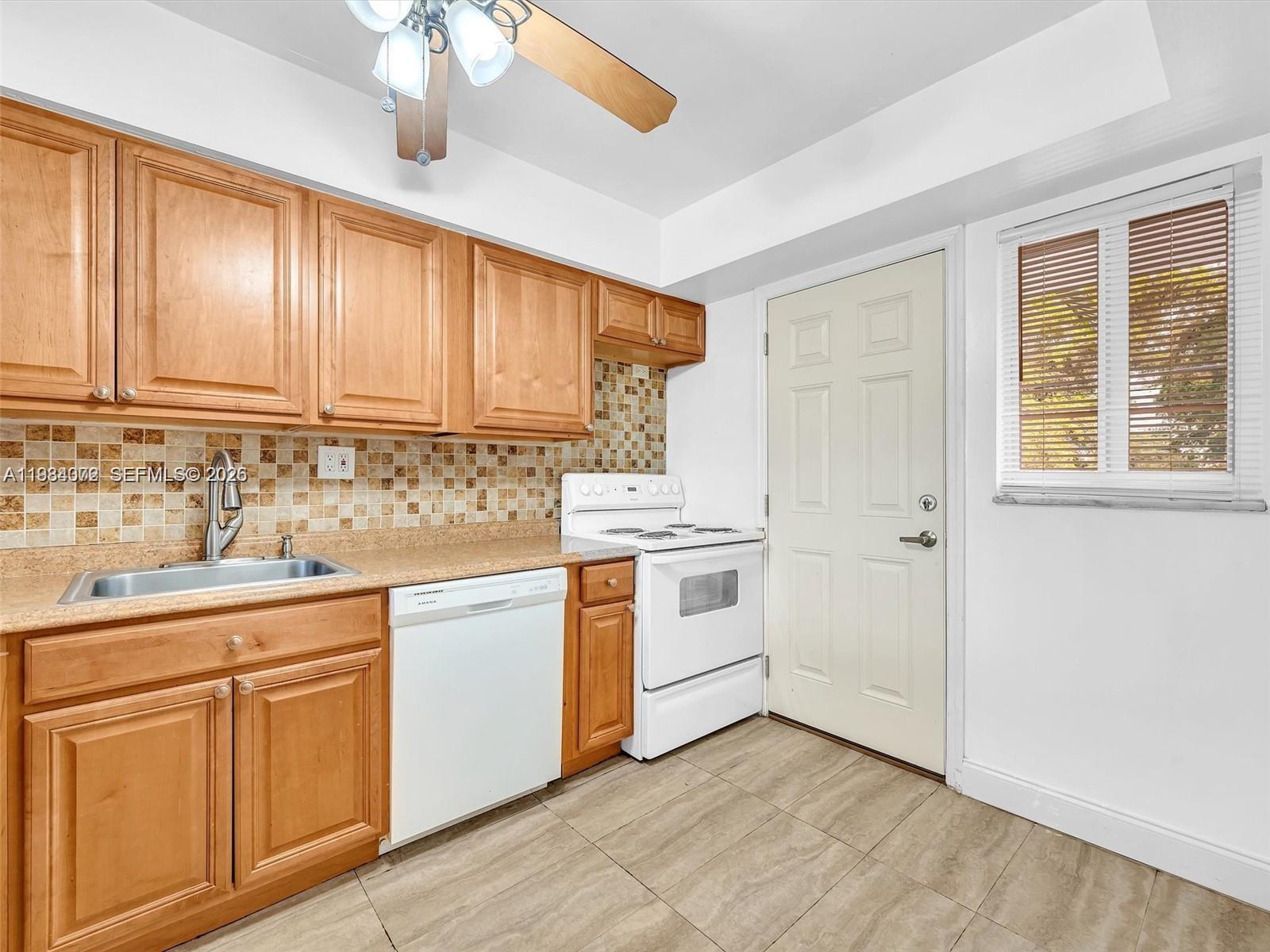 A kitchen features wooden cabinets, a white dishwasher, a white stove, and a tiled backsplash — 1170 NE 191st St # 24, Miami FL 33179, MIAMI, FL