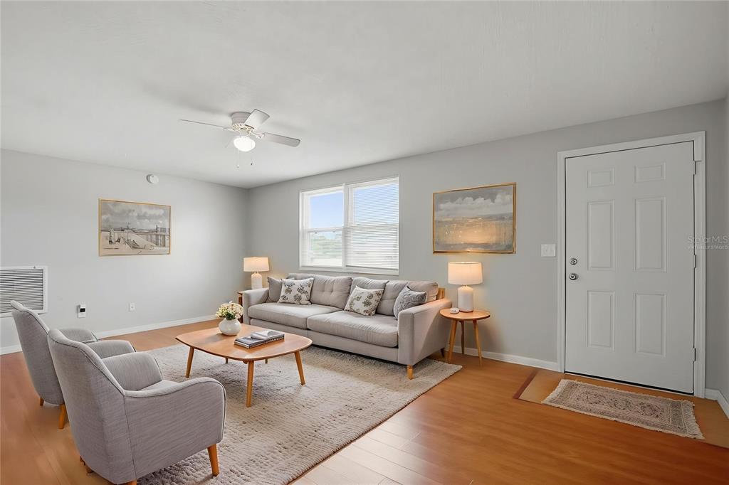 A living room features light gray walls, a gray sofa, two armchairs, and wood flooring — 4374 ORIOLE AVENUE, SPRING HILL, FL