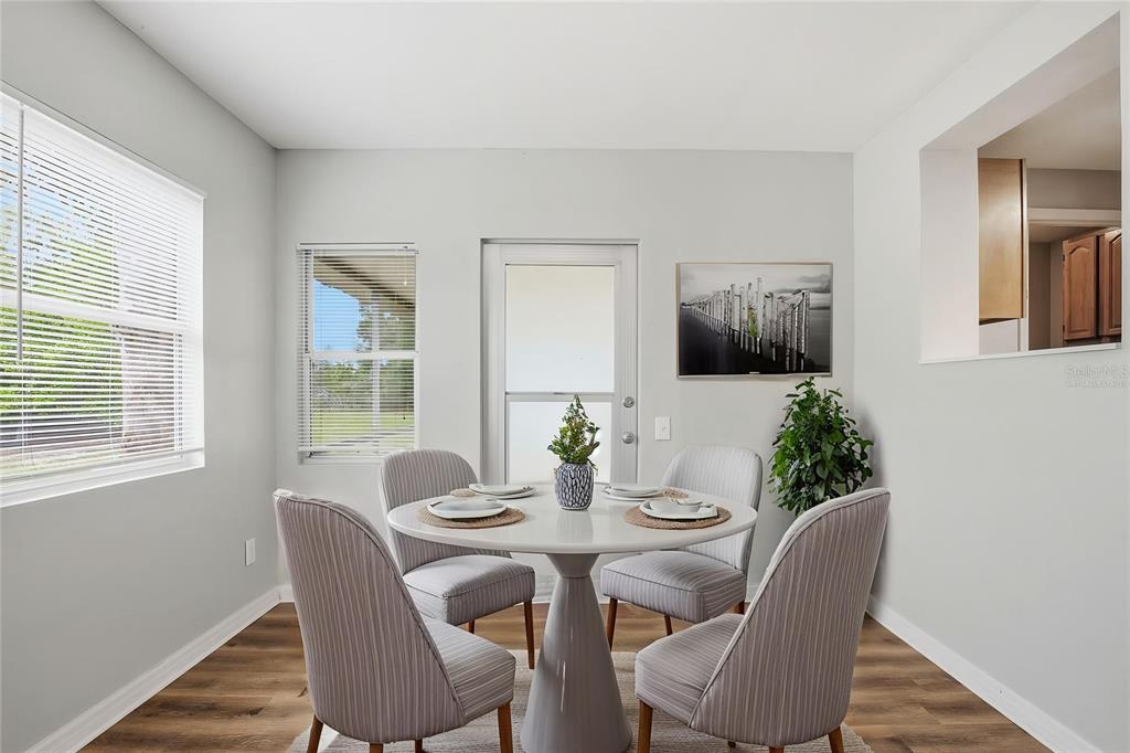 A dining area features a round white table, four striped chairs, and wood-look flooring — 4374 ORIOLE AVENUE, SPRING HILL, FL