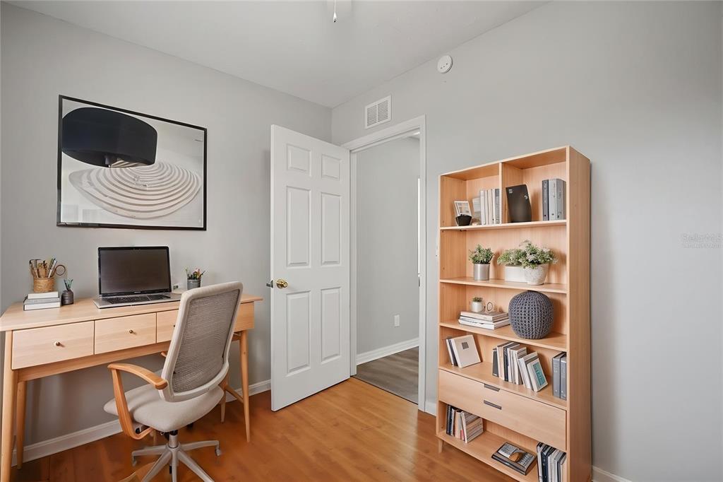A home office features a wooden desk, a rolling chair, and a tall bookshelf — 4374 ORIOLE AVENUE, SPRING HILL, FL
