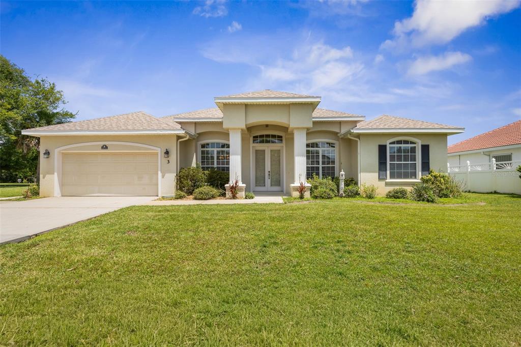 A single-story house with a beige stucco exterior, a two-car garage, and a columned entryway — 3 COCHRAN LANE, PALM COAST, FL