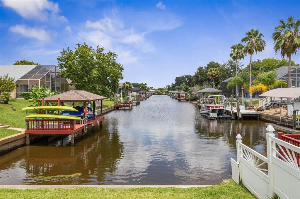 A canal view from a backyard featuring boat docks, covered slips, and residential homes — 3 COCHRAN LANE, PALM COAST, FL