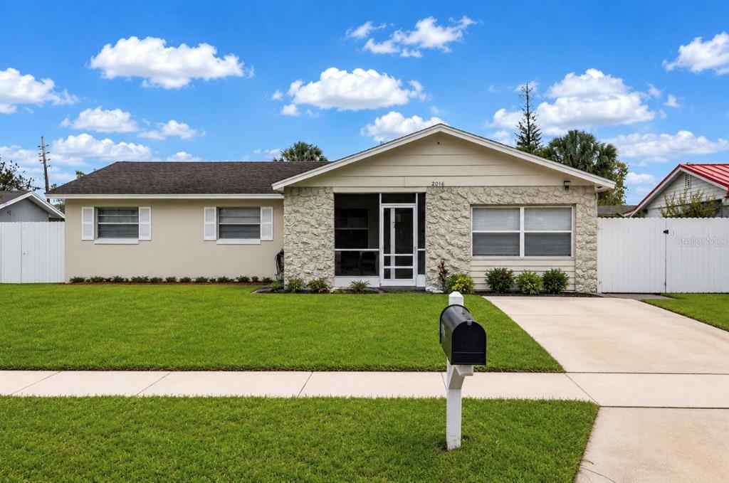 A single-story house with a stone facade, screened porch, and a green lawn — 2016 VALENCIA CIRCLE, KISSIMMEE, FL