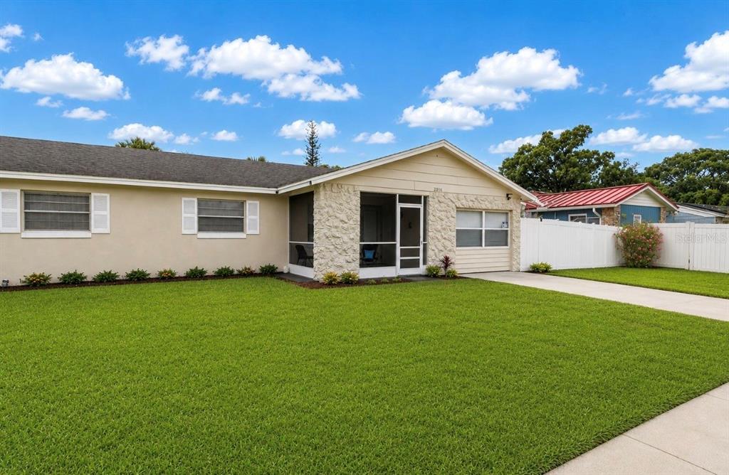 A single-story house with a stone-accented entryway, screened porch, and a white vinyl fence — 2016 VALENCIA CIRCLE, KISSIMMEE, FL