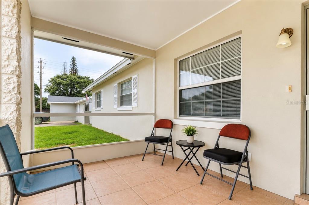 A screened-in porch features tiled flooring, three chairs, a small side table, and exterior views — 2016 VALENCIA CIRCLE, KISSIMMEE, FL