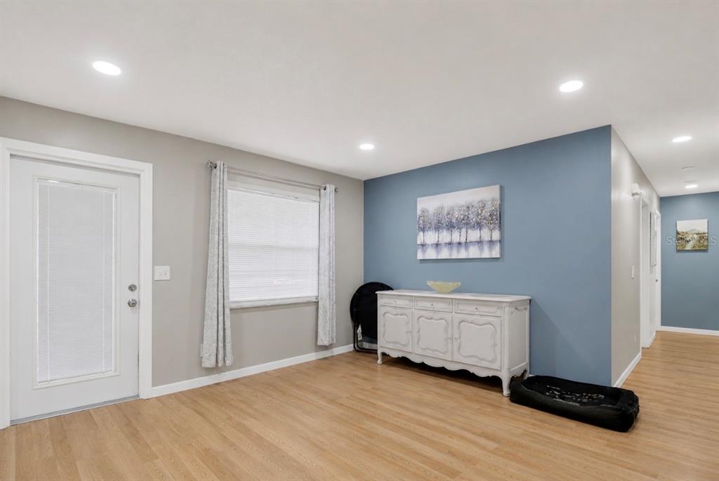 A room with light wood flooring, a blue accent wall, and a white sideboard — 2016 VALENCIA CIRCLE, KISSIMMEE, FL