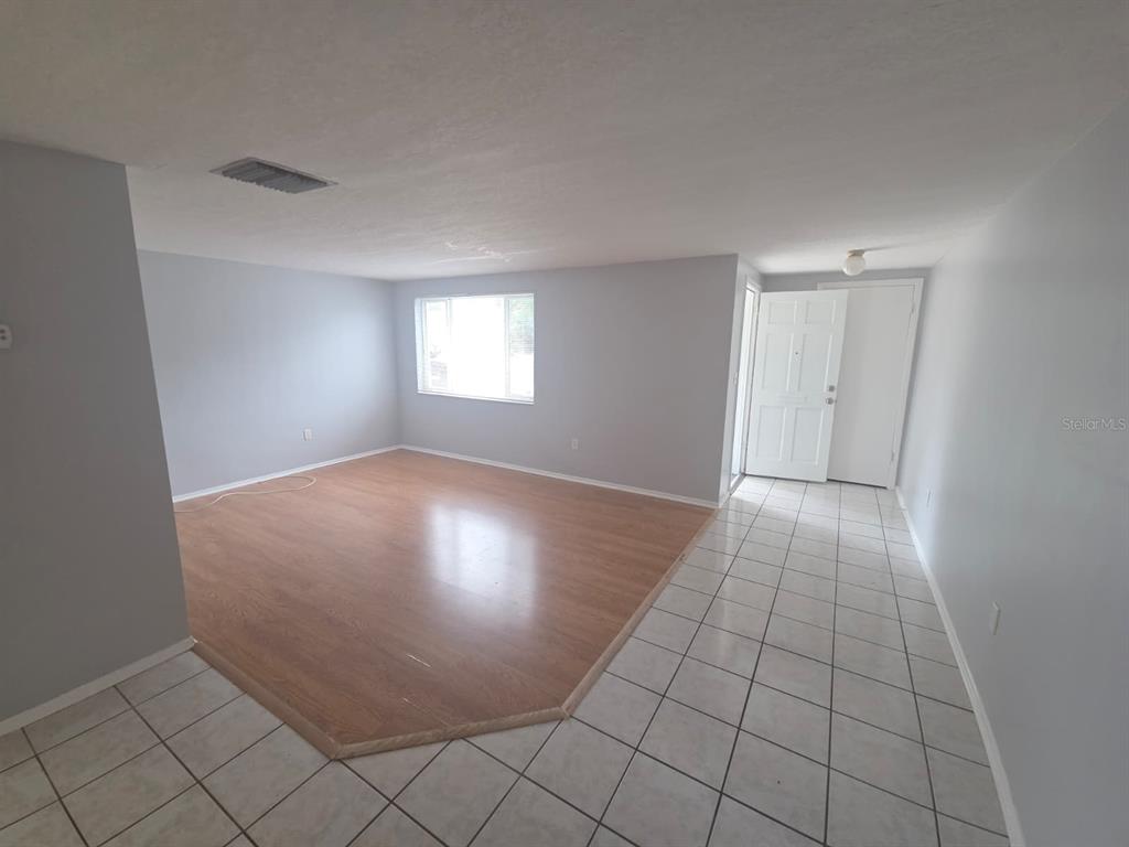 An interior view showing a living area with wood flooring, tiled entryway, and white walls — 3619 SPRINGFIELD DRIVE, HOLIDAY, FL