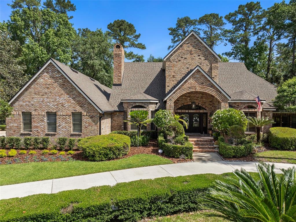 A brick house with a gabled roof, arched entryway, and landscaped front yard — 2214 EARLEAF COURT, LONGWOOD, FL