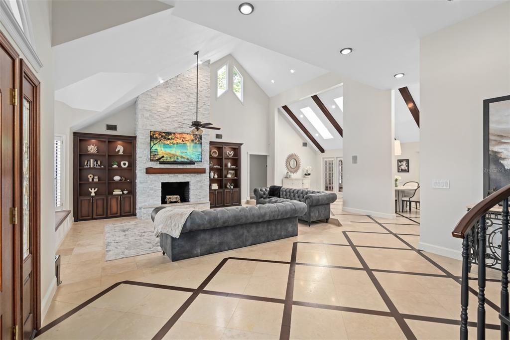 A living room with a stone fireplace, vaulted ceilings, and tile flooring with dark inlays — 2214 EARLEAF COURT, LONGWOOD, FL
