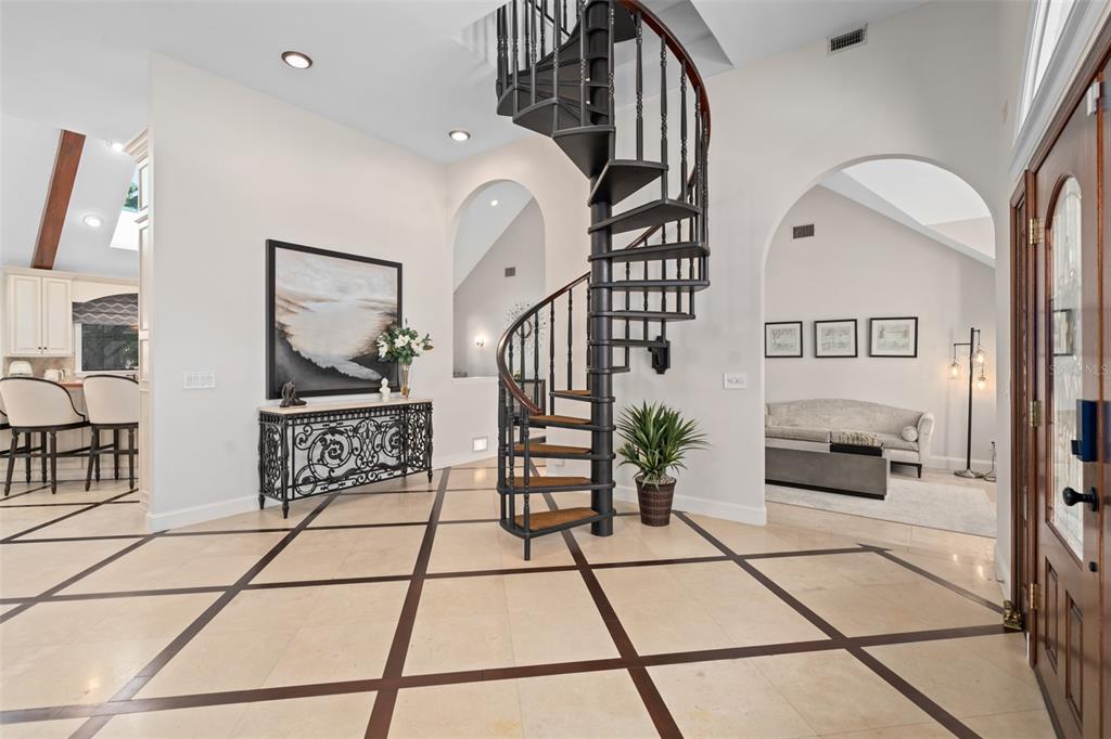 A foyer features a black spiral staircase, tile flooring with dark inlays, and arched doorways — 2214 EARLEAF COURT, LONGWOOD, FL