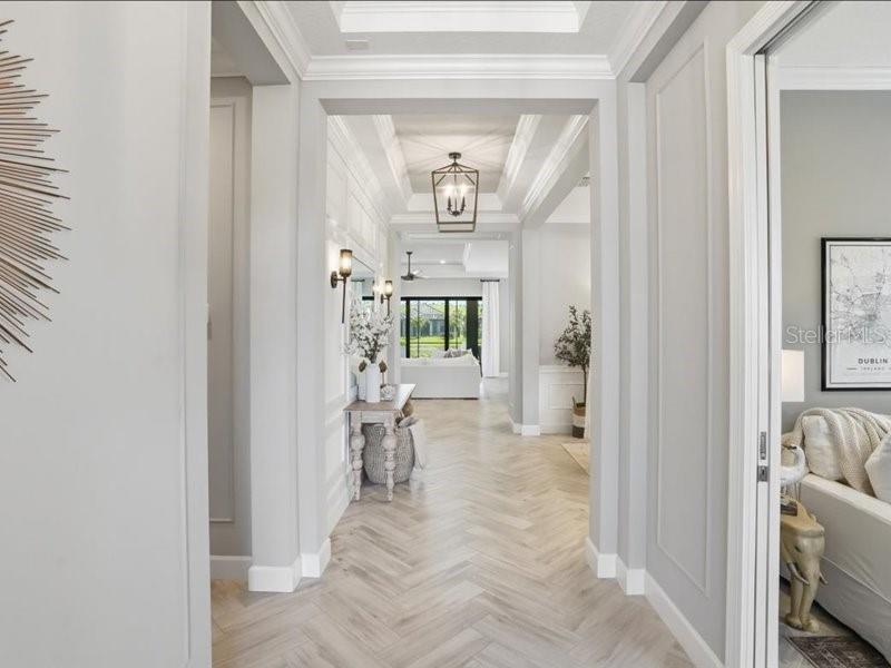 A bright hallway with herringbone wood floors leads toward an open living area — 6243 PLATEAU COURT, BRADENTON, FL