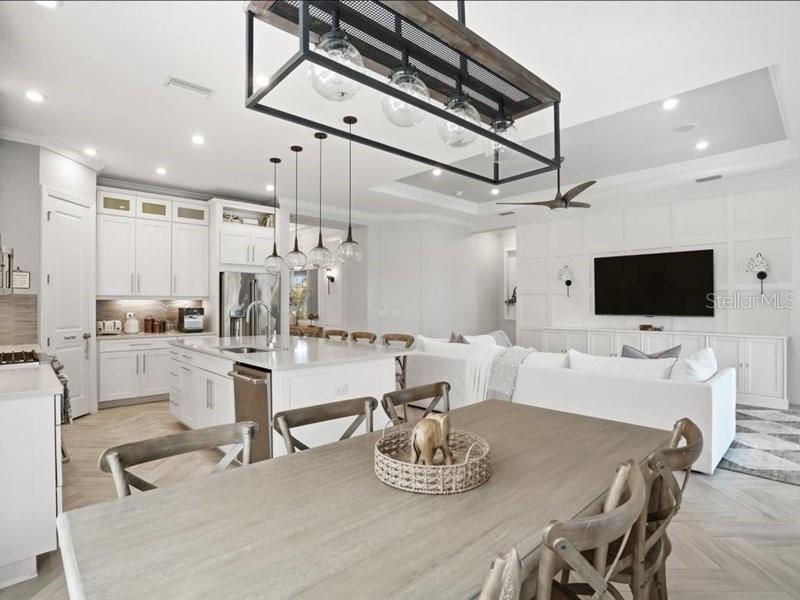 An open-concept kitchen and dining area features white cabinetry, a large island, and wood flooring — 6243 PLATEAU COURT, BRADENTON, FL