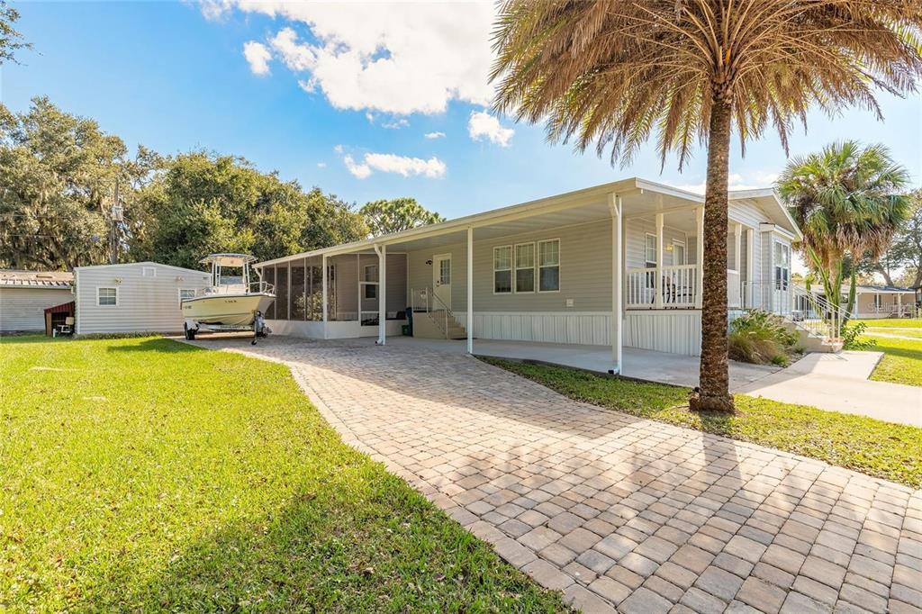 A single-story mobile home with a paved driveway, carport, and a boat parked outside — 152 RED BASS LANE, EDGEWATER, FL